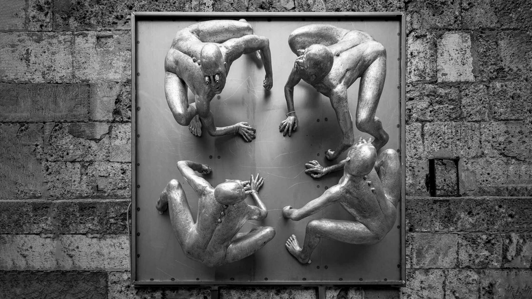 Skulptur 4 Personen an der Wand