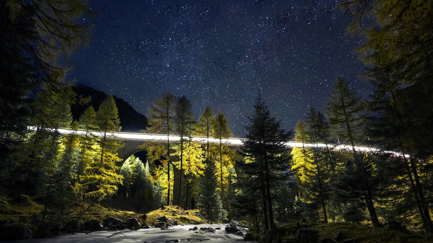 Langzeitbelichtung Zug auf Brücke bei Nacht